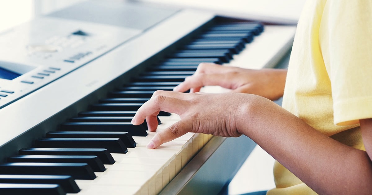 Child's hands playing digital piano