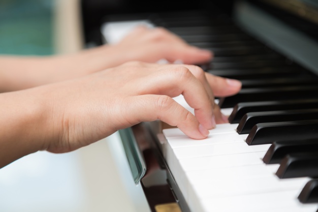 side view of two hands playing piano during online piano lesson